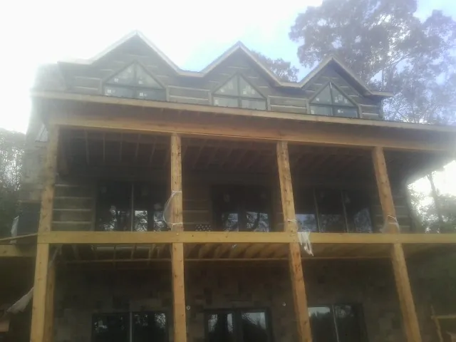 Dormers and porch framing on a large log home under construction — Roof Coating work by our crew in Cooperstown